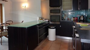 Una cocina moderna con gabinetes negros, una isla de vidrio, electrodomésticos de acero inoxidable y un cesto de basura.