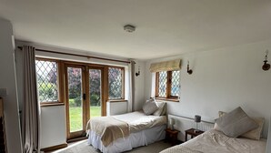 Un dormitorio con dos camas, ventanas amplias y vistas a zonas verdes.