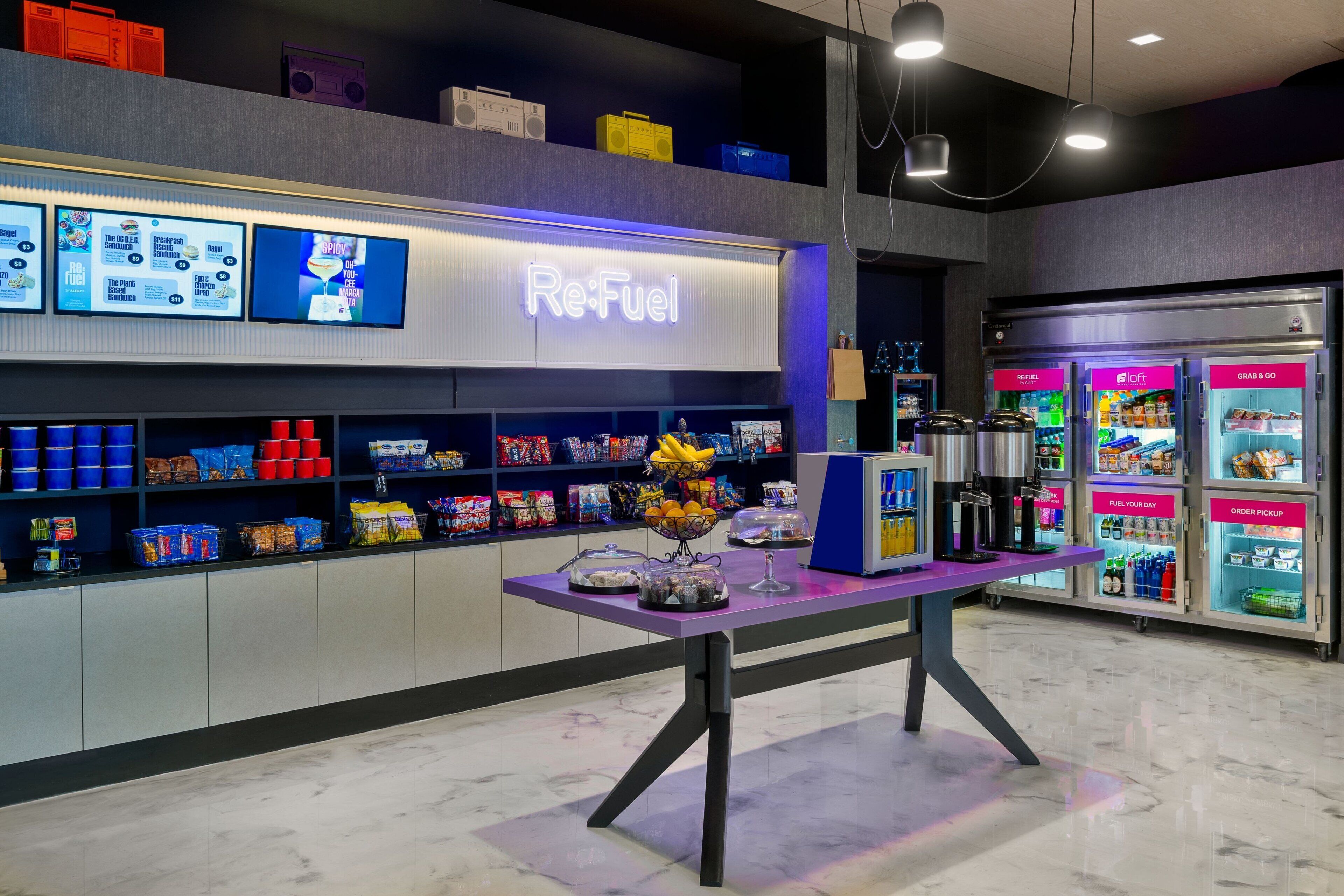 A Re:Fuel station with a purple counter, snack dispensers, and a digital menu board.