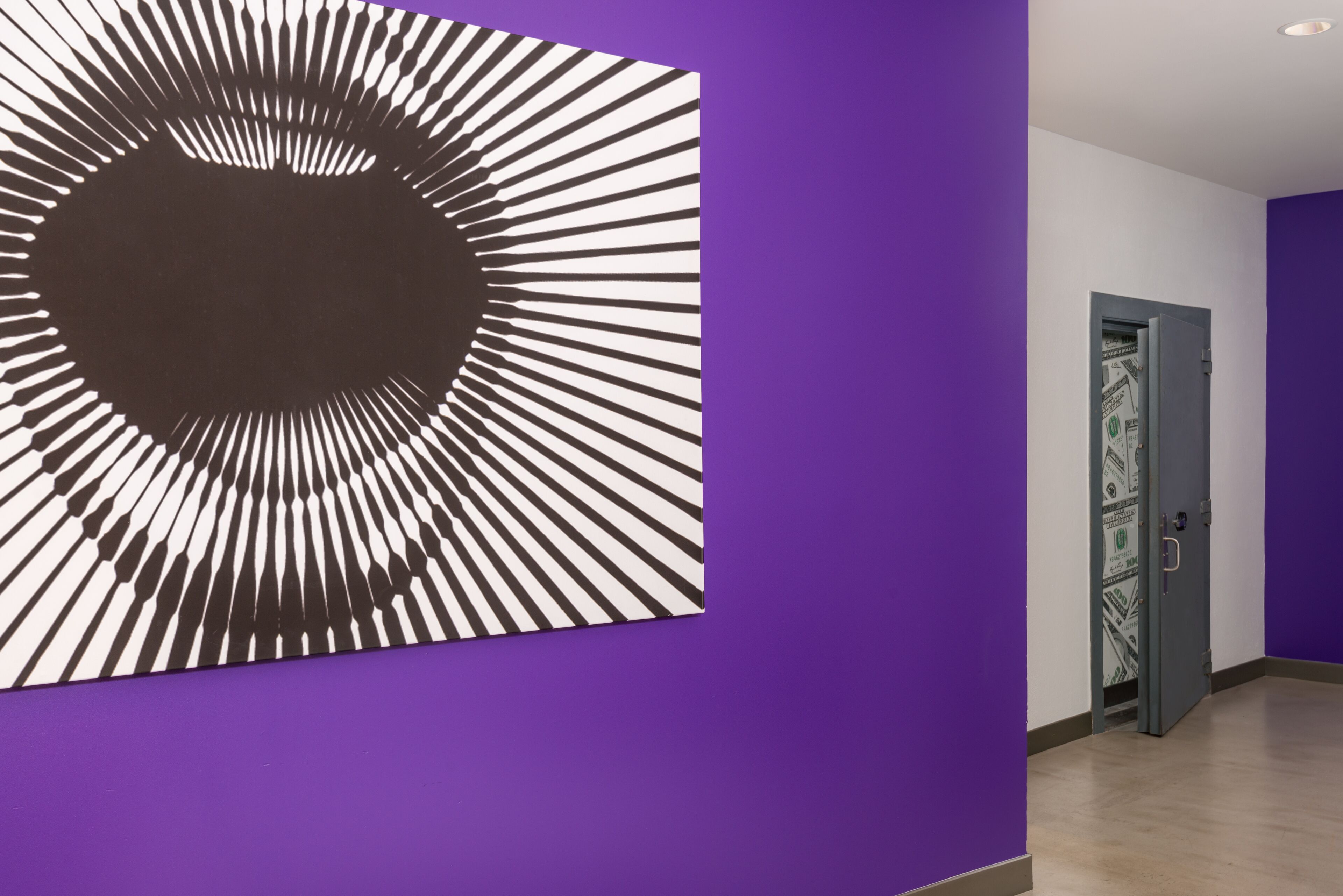 Een gang met een paarse muur en een groot abstract kunstwerk.