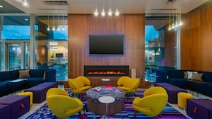 A modern lounge area with a central fire feature, comfortable seating, and a large flat-screen TV.