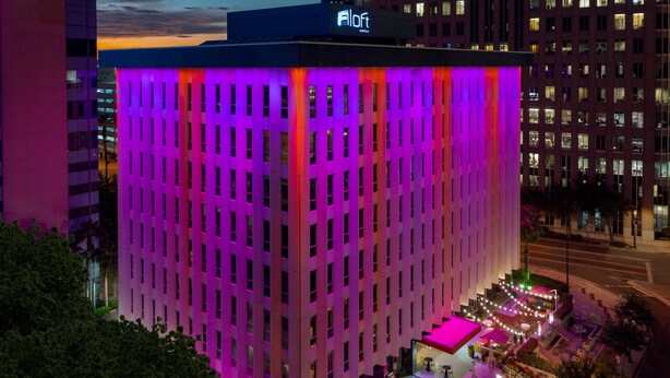 A hotel with a modern facade, multiple floors, and a rooftop pool area.