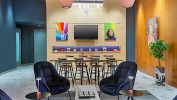 A modern lobby with a bar area, seating, and a TV screen.