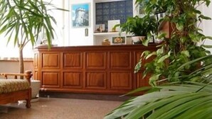 A living room with a patterned sofa, wooden cabinet, and potted plants. - Motel Monterosa (Vogogna)