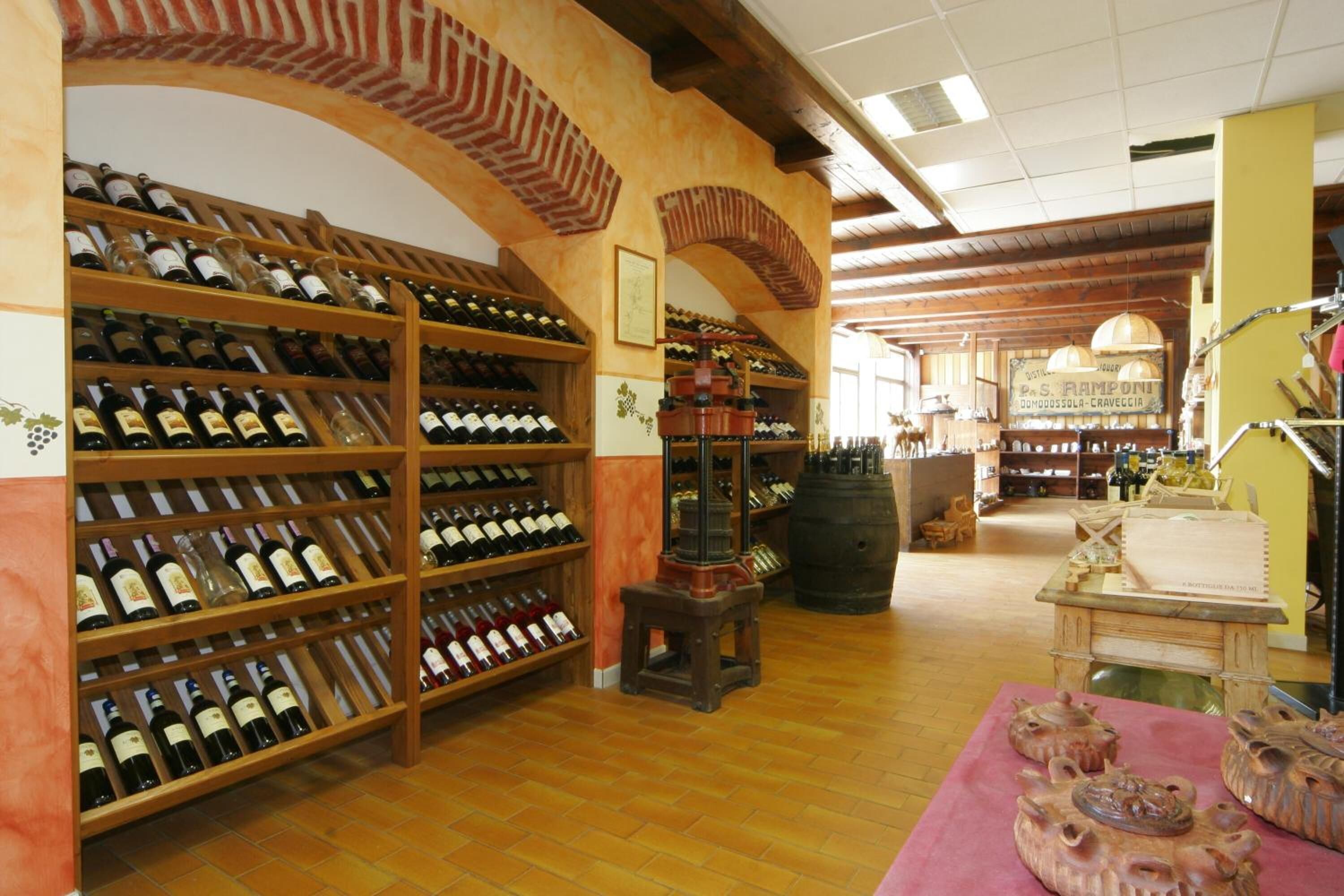 A wine cellar with wooden shelves and barrels, a wine rack, and a table with pottery.