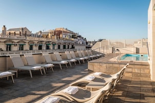A rooftop pool area with lounge chairs and a swimming pool.