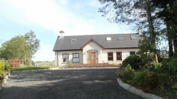 A two-story house with a front porch, a driveway, and a well-maintained garden. - Teach an Cheoil (Ballycastle)
