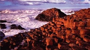 A coastal landscape with a rocky outcrop and waves crashing against the shore. - Teach an Cheoil (Ballycastle)