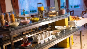 A buffet setup with various food items and condiments. - Christiania Wellness Hotel (Saas Almagell)