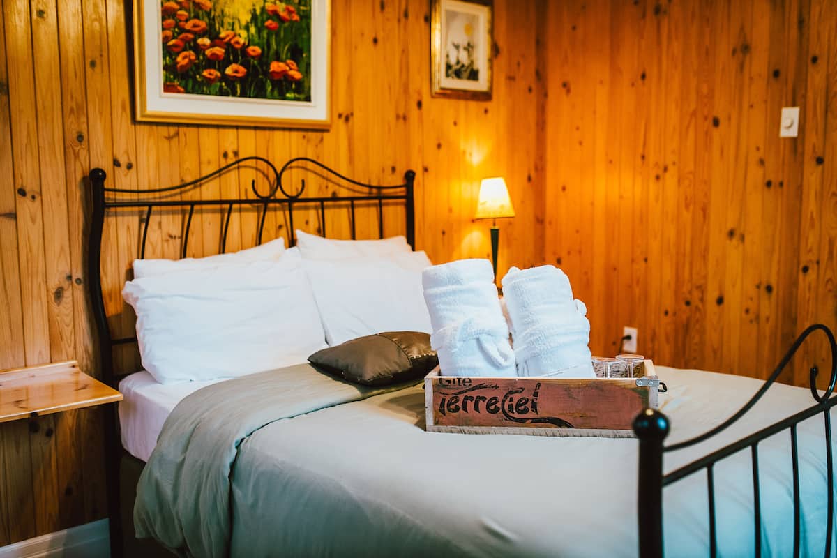 A neatly made bed with white linens, a wooden headboard, and a bedside table with a lamp.