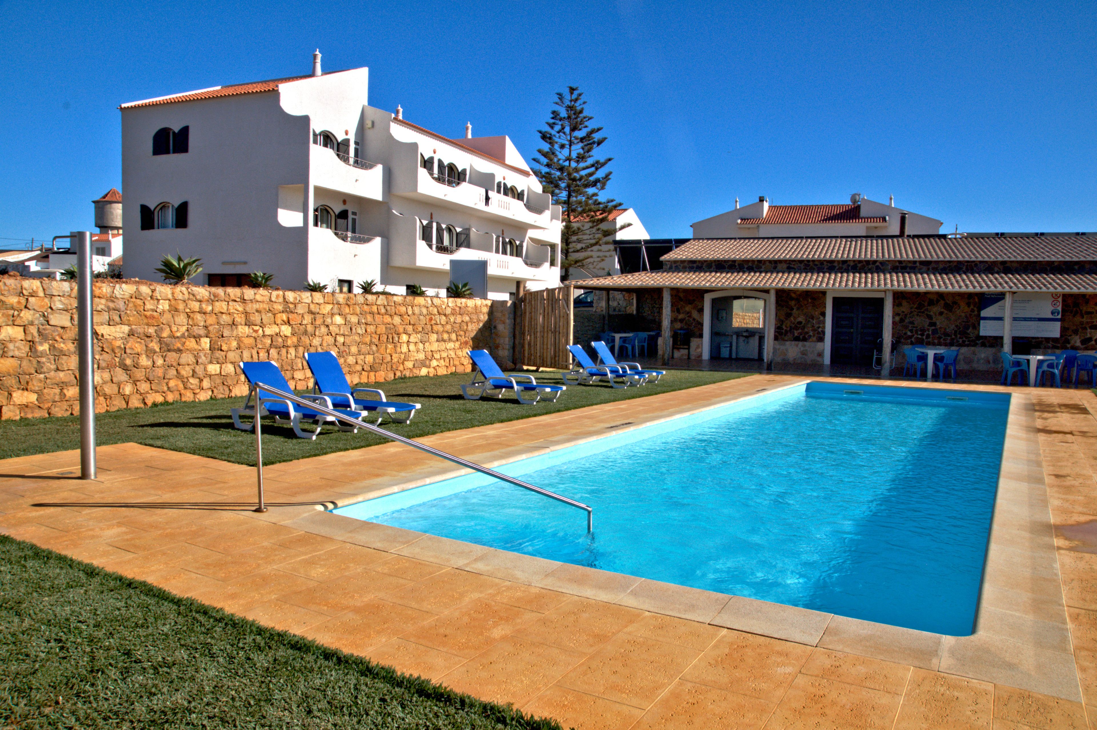 Een seizoensgebonden buitenzwembad, ligstoelen bij het zwembad