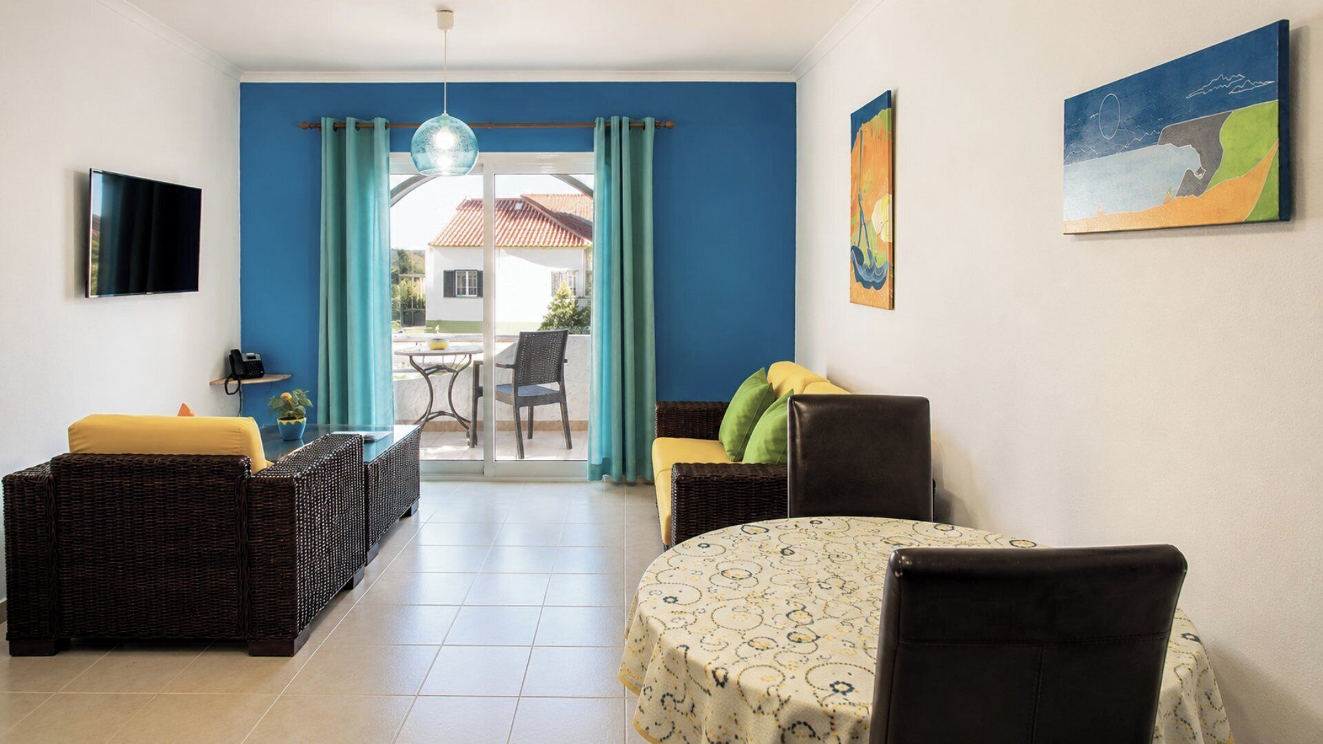 Una habitación con una mesa de comedor, dos sofás, un televisor y vistas al exterior.