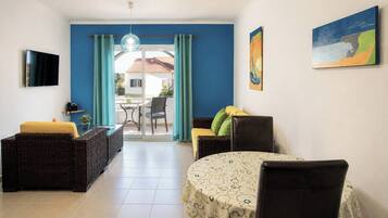 Una habitación con una mesa de comedor, dos sofás, un televisor y vistas al exterior.