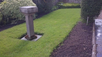A well-maintained garden with a stone monument, neatly trimmed grass, and a pathway.