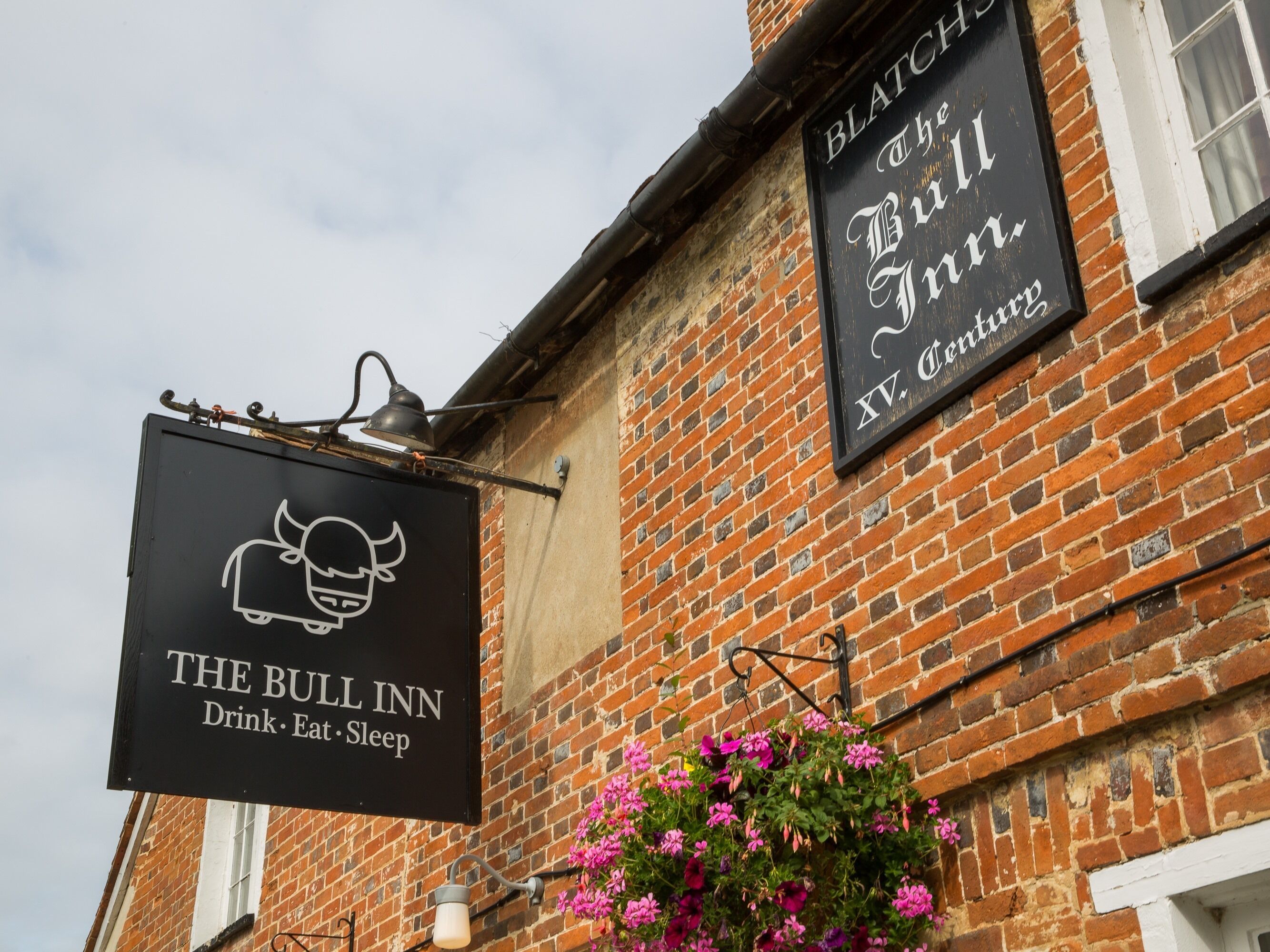 Un edificio de ladrillo con dos letreros: uno dice 'The Bull Inn' y otro 'Blatch's the Bull Inn'.