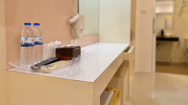 A hotel room counter with a mirror, a hairdryer, two water bottles, a remote control, and a tissue box. - Patong Platinums (Patong)