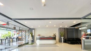 A modern reception area with a reception desk labeled "PATONG PLATINUMS," glass walls, a seating area with chairs, and a large potted plant. - Patong Platinums (Patong)