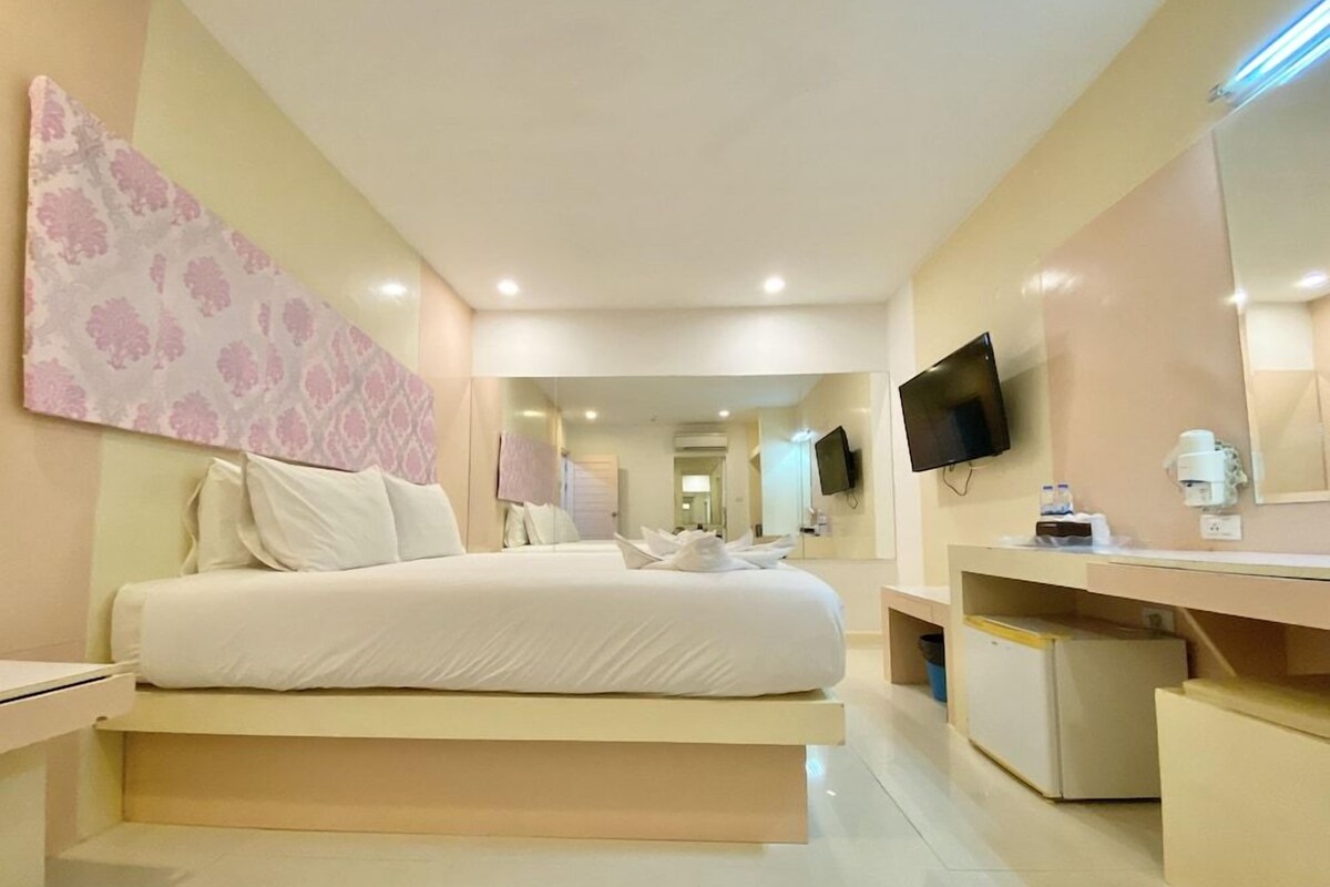 Une chambre d’hôtel avec un grand lit, un bureau, une télévision et un miroir.