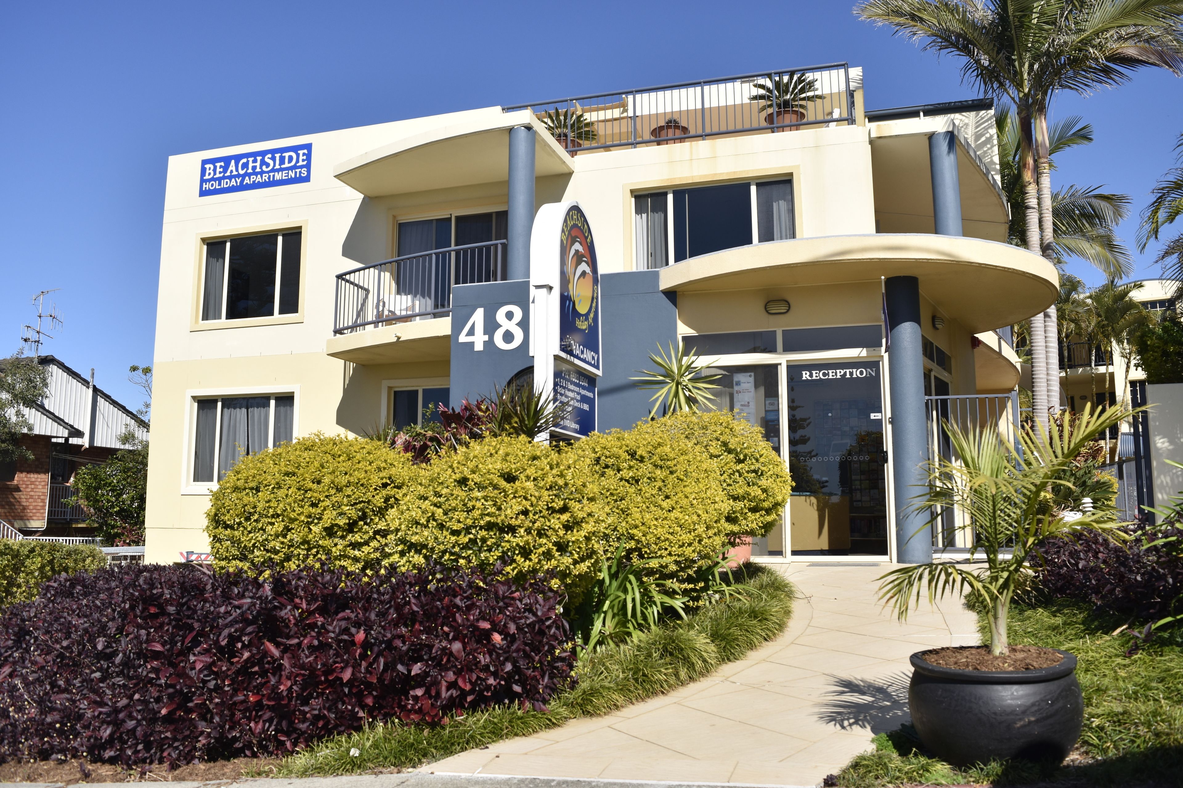 A multi-story building with a sign reading "Beachside Holiday Apartments."