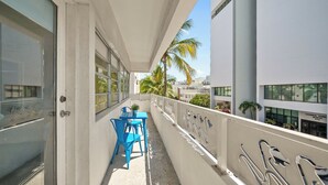 A balcony with a table and chairs, a door, and a railing with graffiti. - Miami International by Lowkl (Miami Beach)