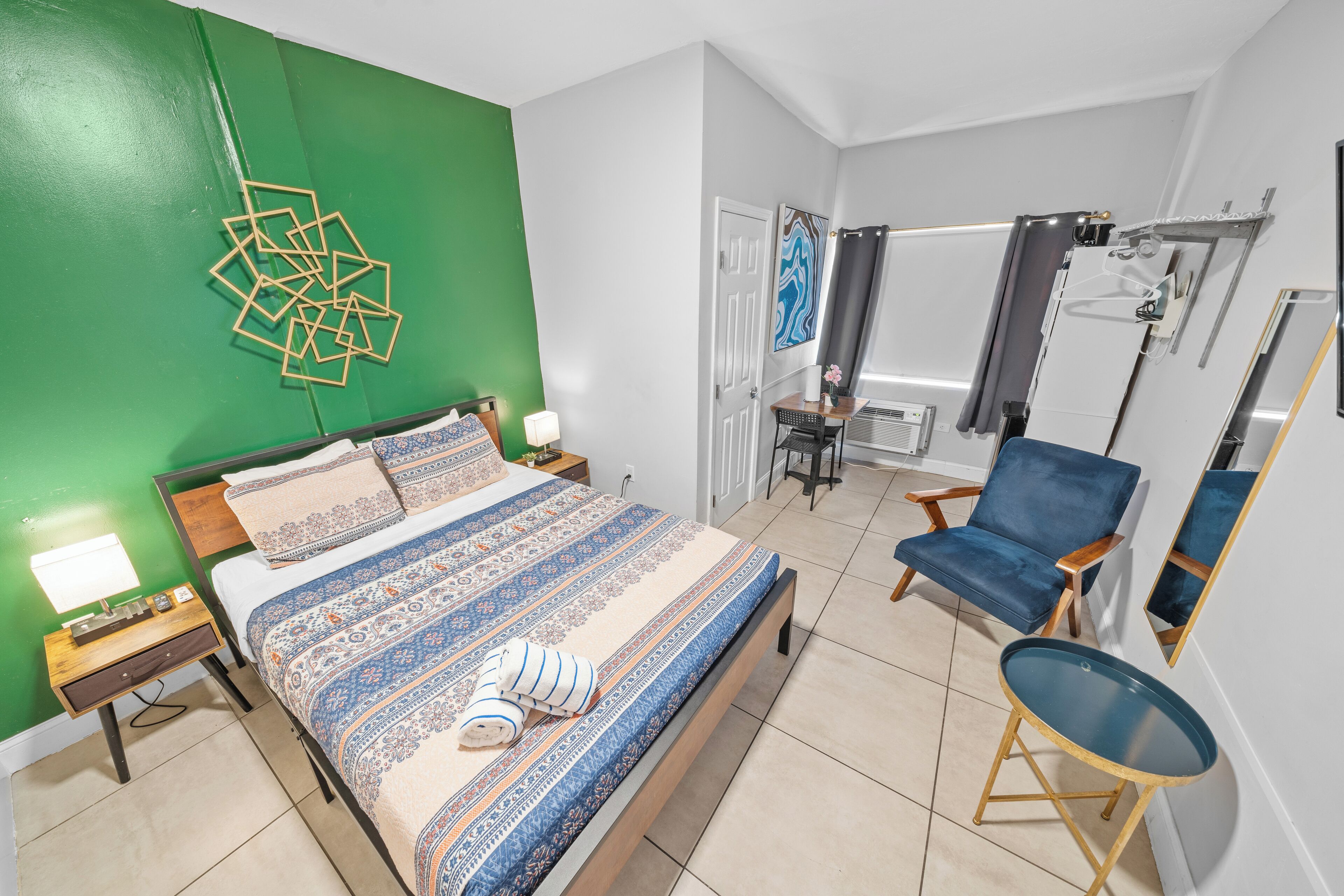 Quarto com uma cama, uma cadeira, uma mesa pequena e um espelho.