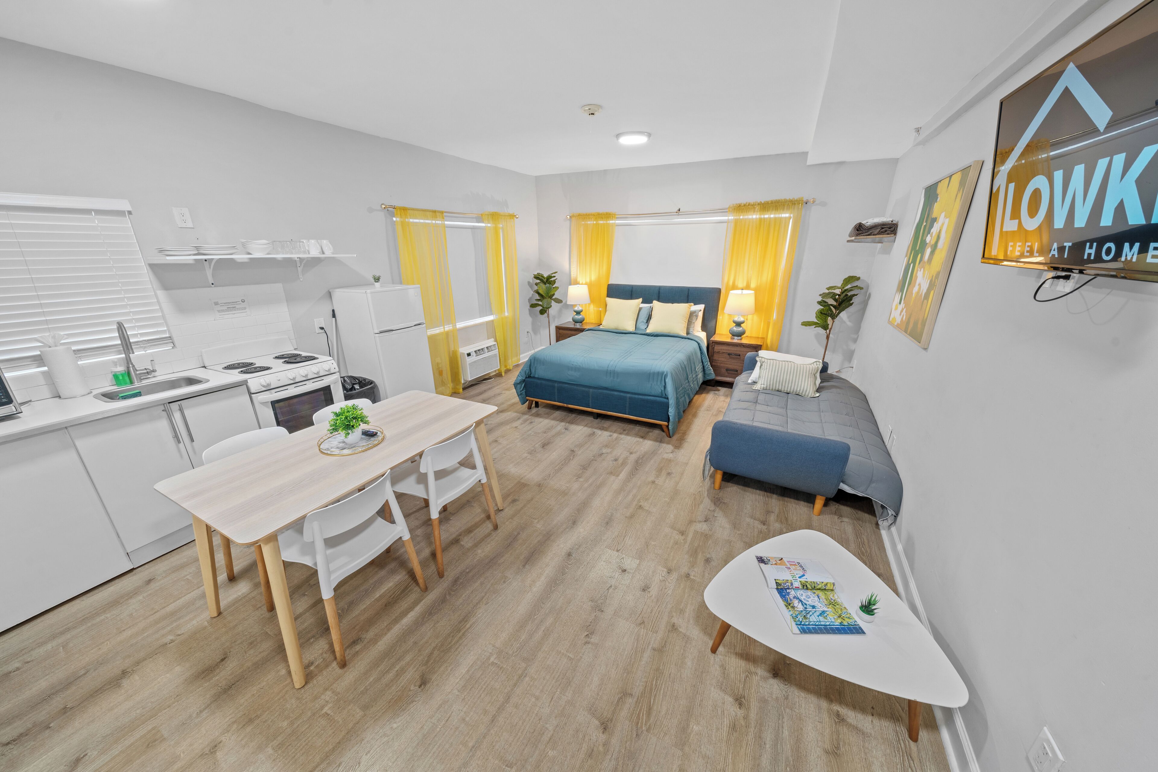 A modern, well-lit room with a bed, bedside table, and a small seating area.