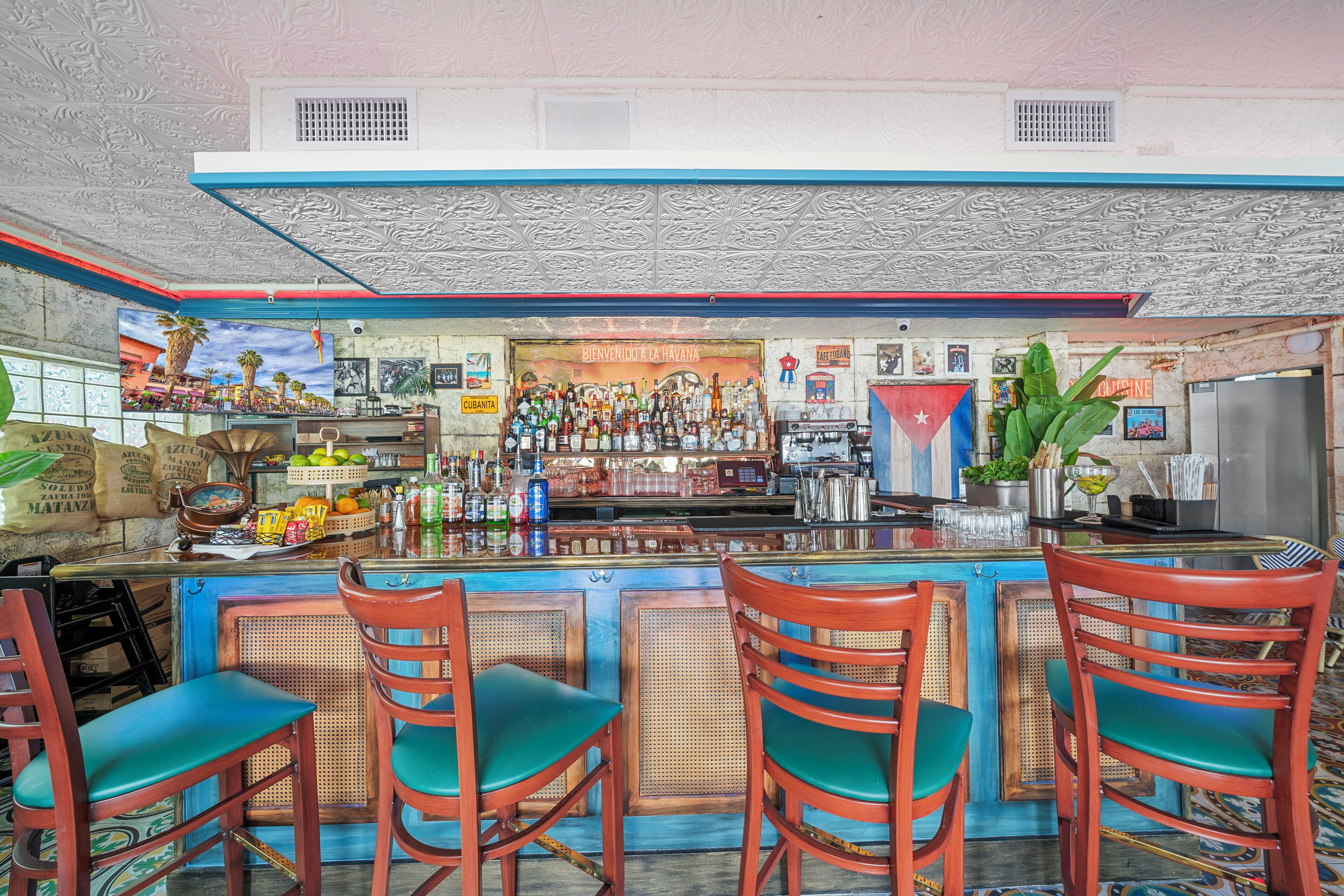 A bar with a counter, bar stools, and a variety of bottles and glasses.