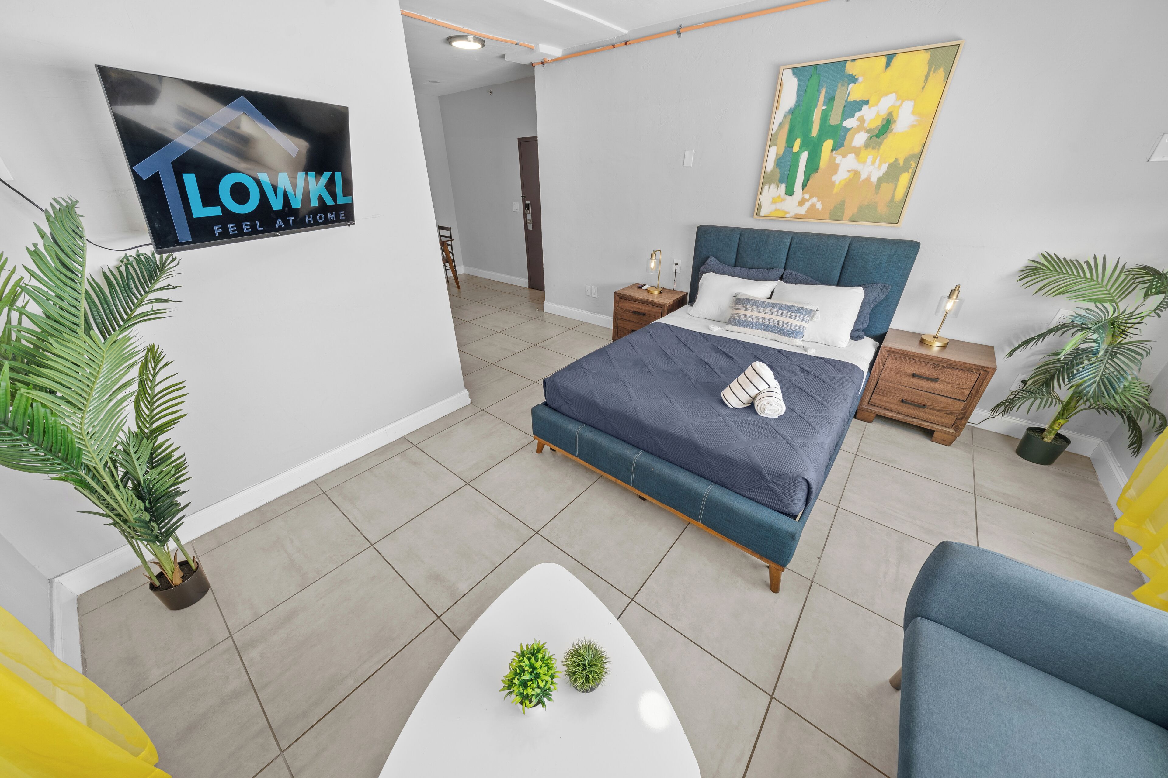 Un dormitorio moderno con una cama, mesitas de noche, un televisor y un cuadro.