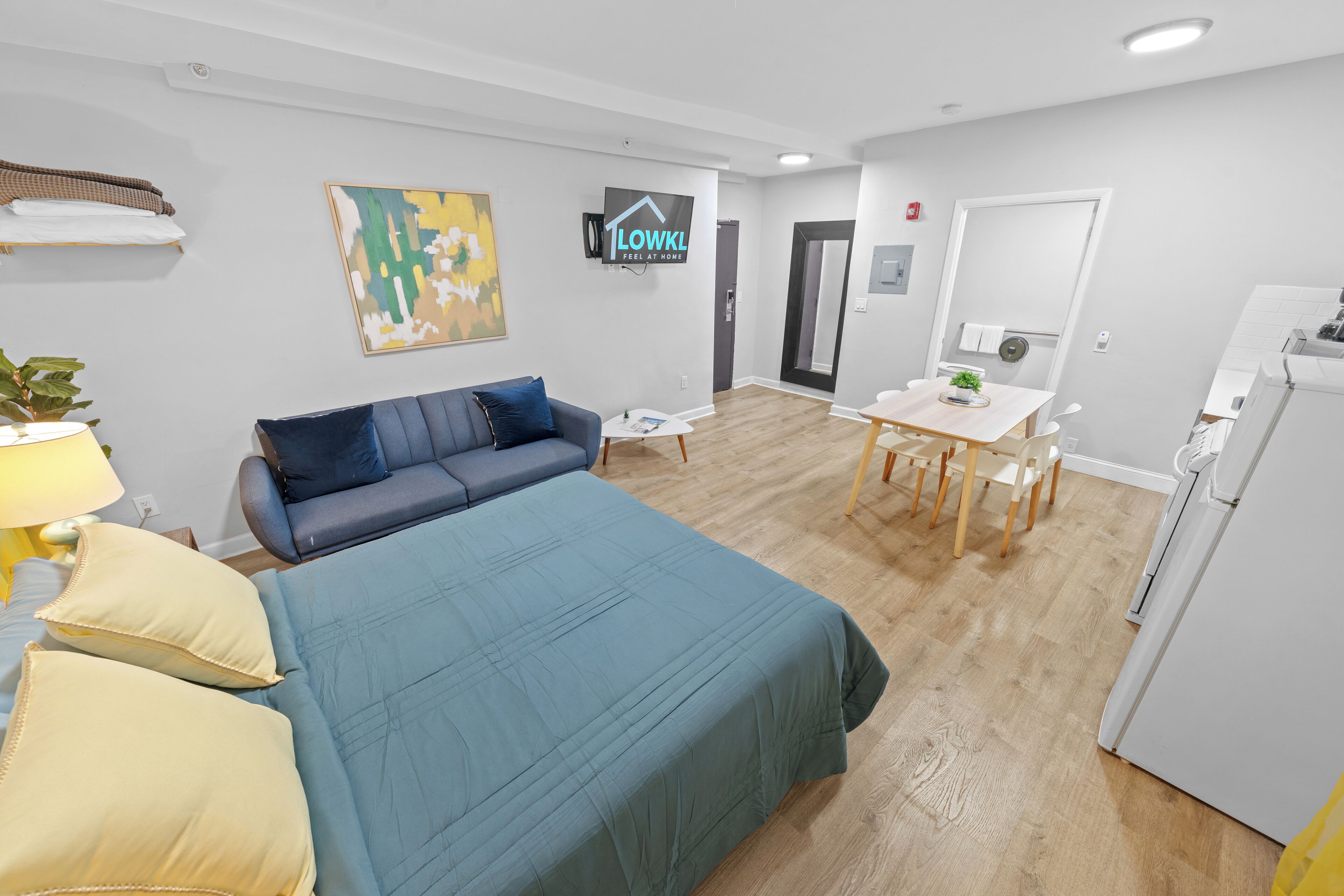Una habitación de hotel moderna con una cama, un sofá, una pequeña mesa de comedor y una zona de cocina.