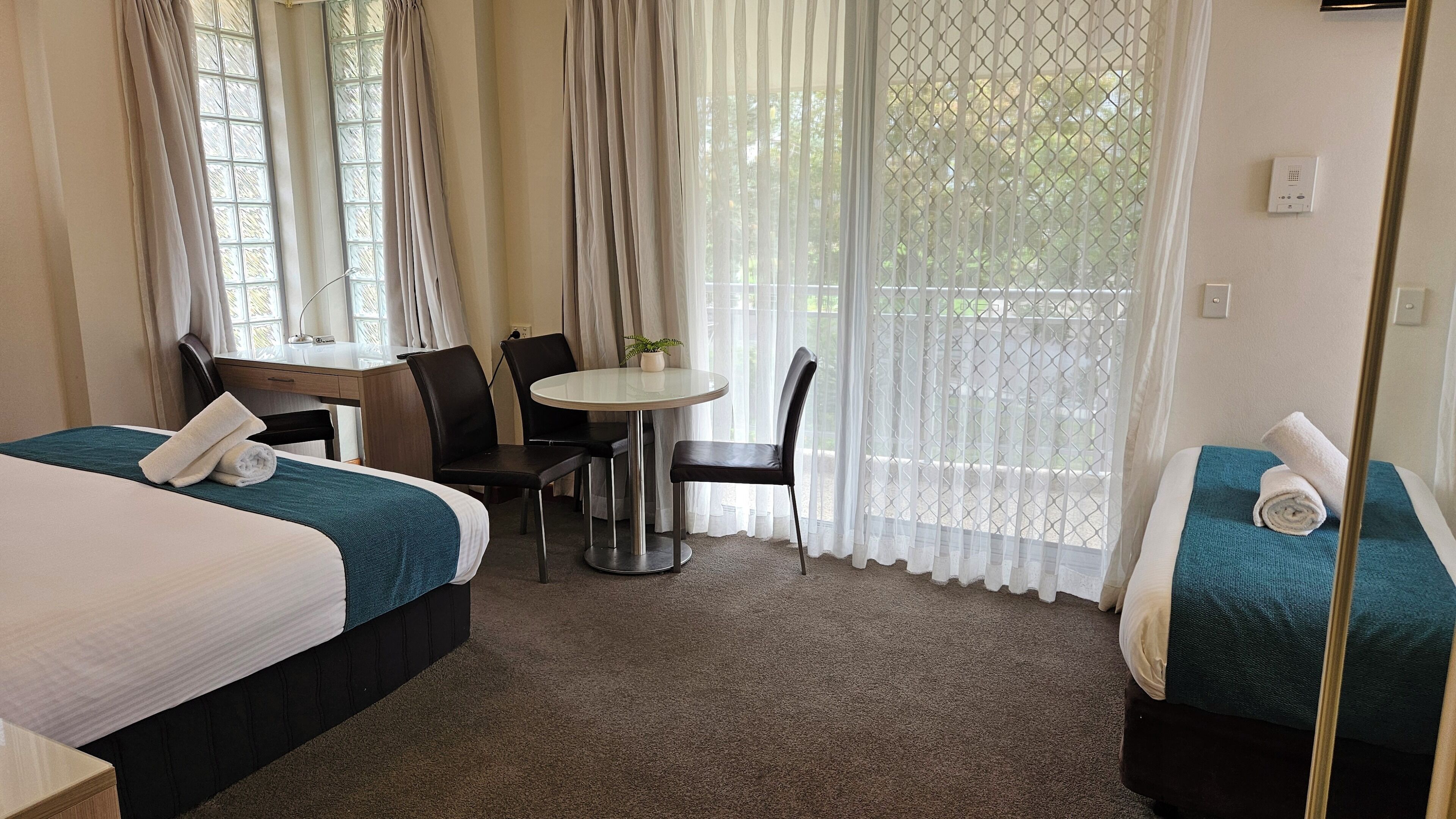 Habitación de hotel con dos camas, una mesita redonda y sillas.