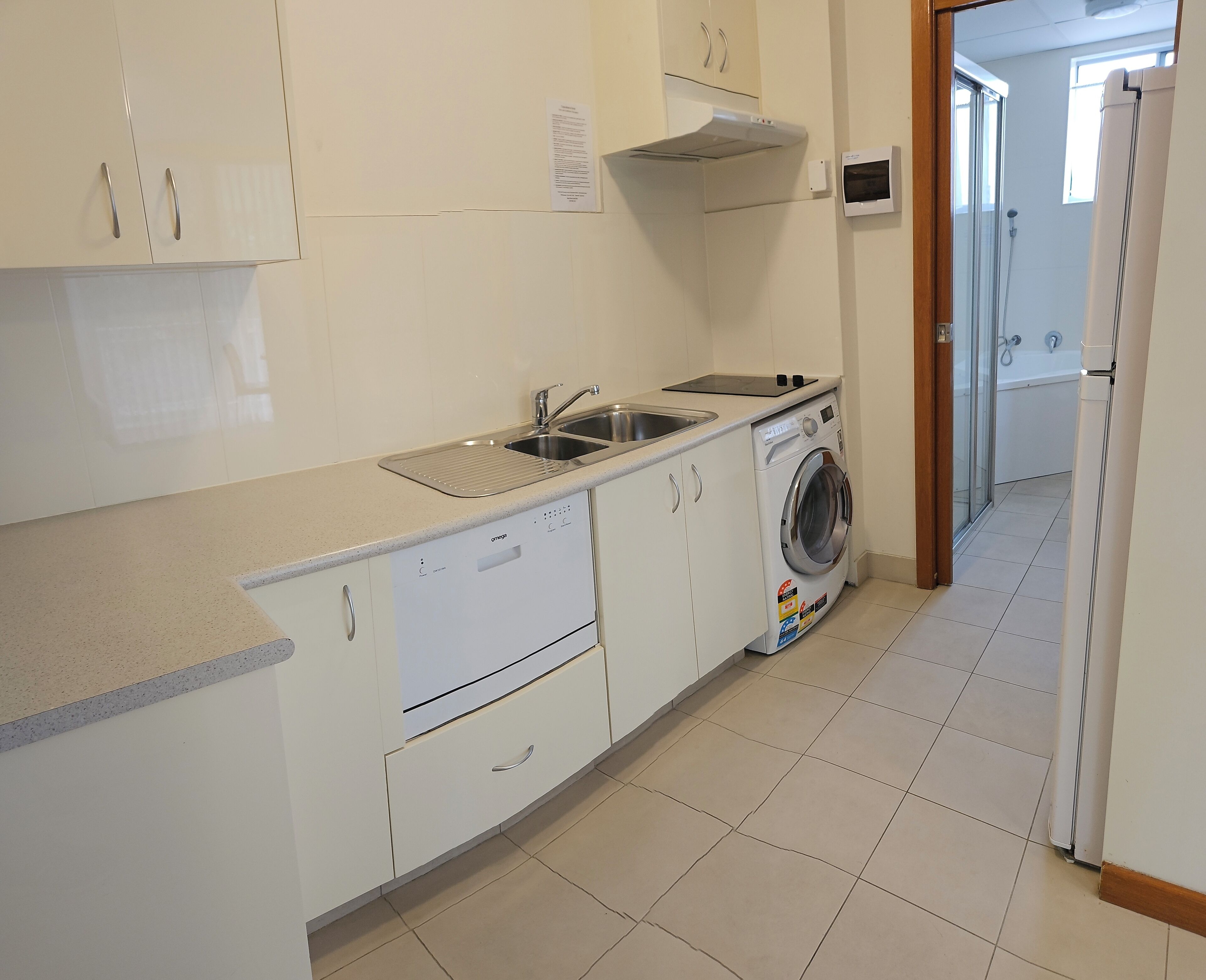 Una cocina moderna con lavadora integrada, un lavabo y una estufa.