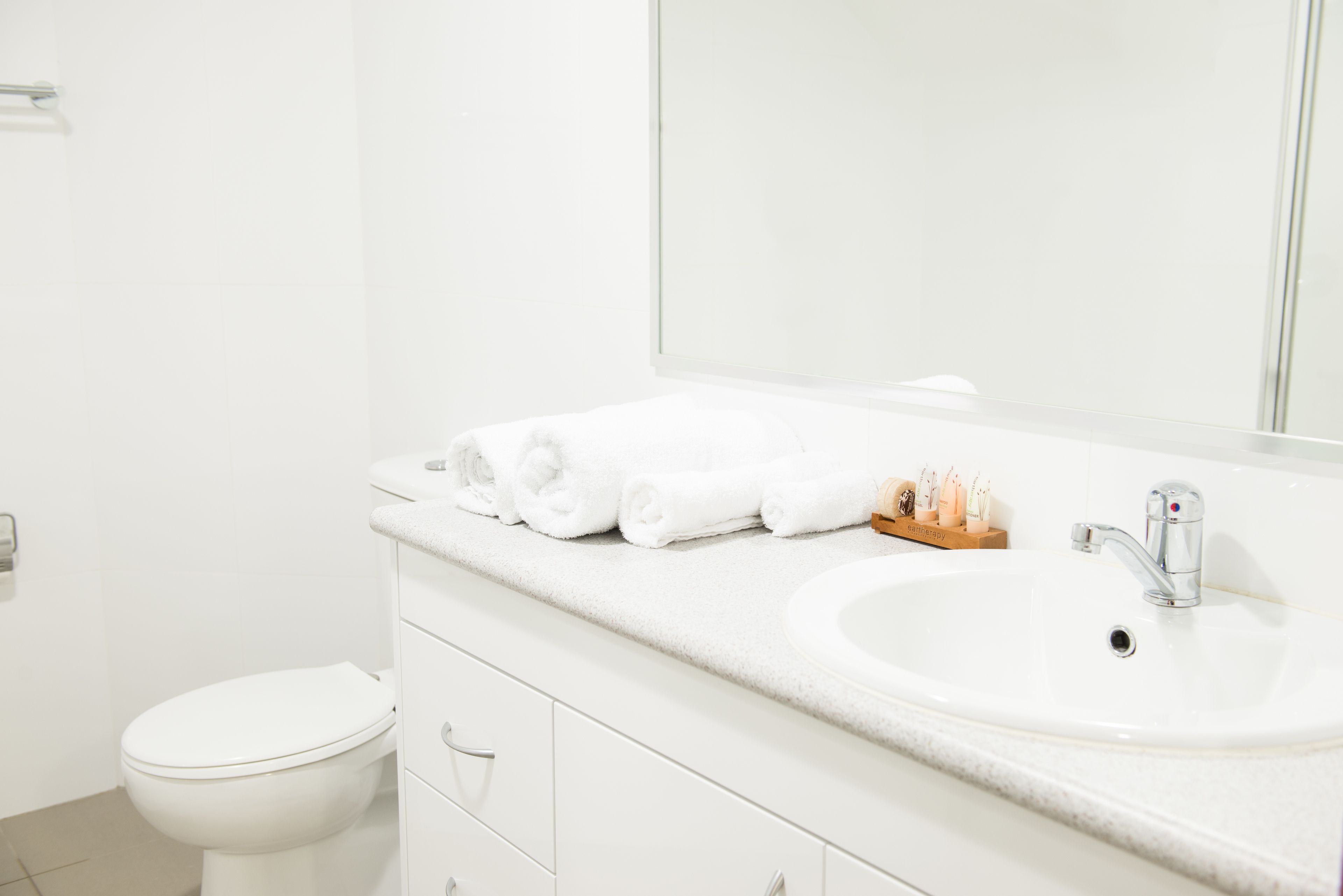 A white bathroom with a sink, mirror, and toilet.