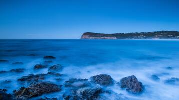 A coastal landscape with rocky terrain and a distant cliff.