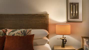 Un lit bien fait, avec des oreillers, une table de chevet avec une lampe et un tableau encadré au mur.