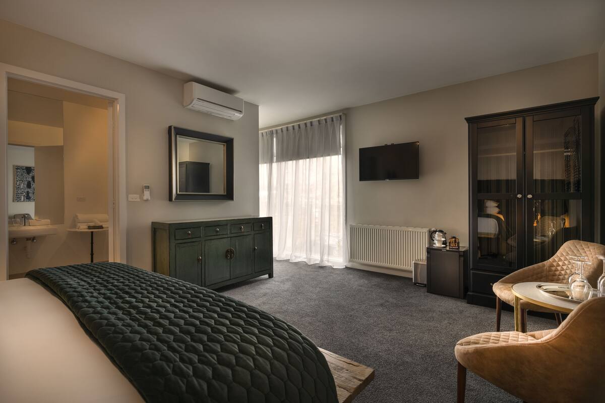 A hotel room with a bed, a dresser, a TV, a cabinet, and a chair.