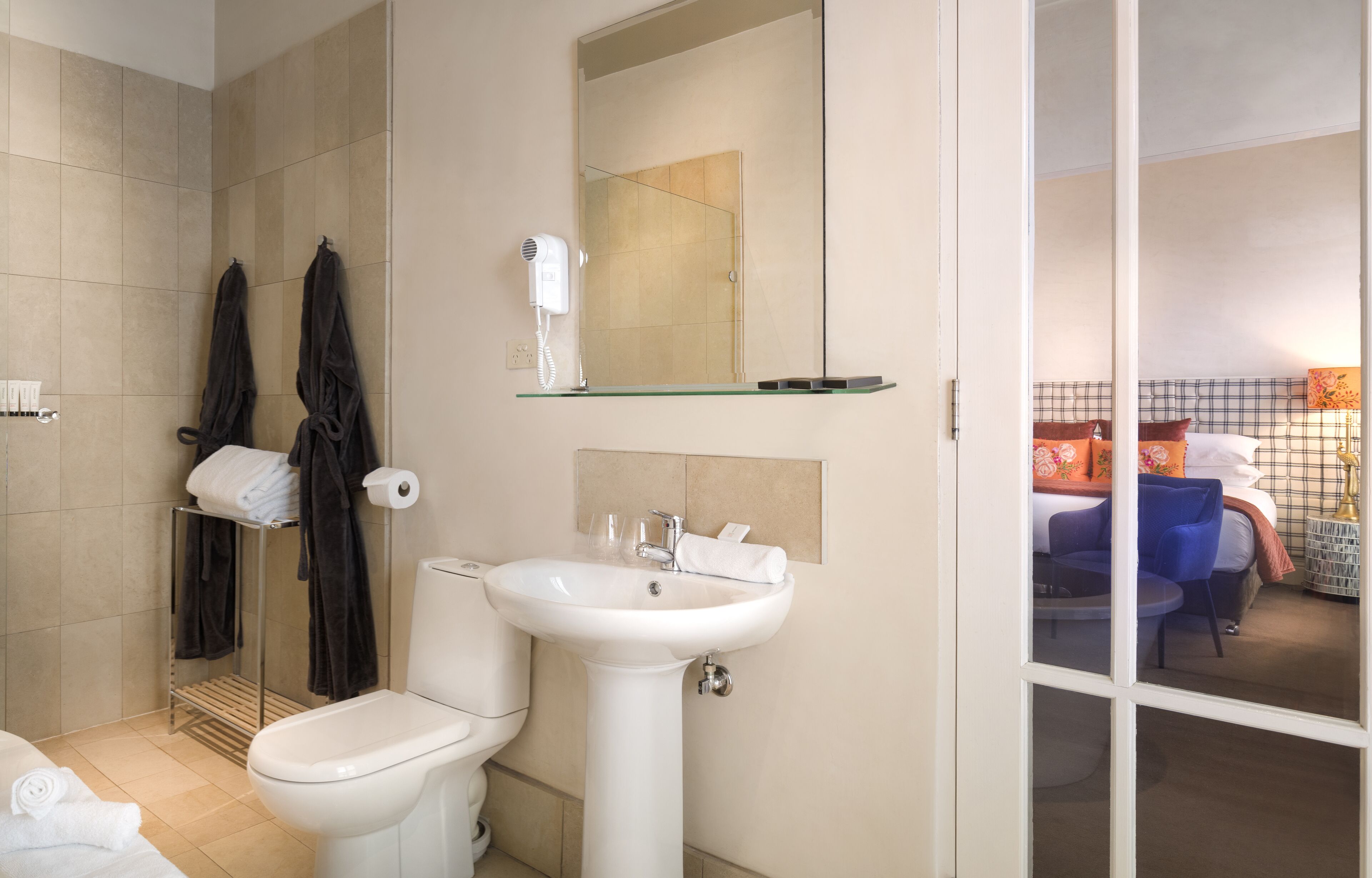 A bathroom with a toilet, sink, towel rack, and a mirror.