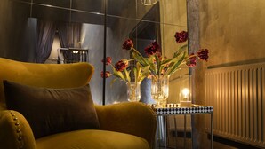 A modern room with a yellow armchair, a glass table with a chessboard, and a vase with red flowers. - Hotel Frangos (Daylesford)