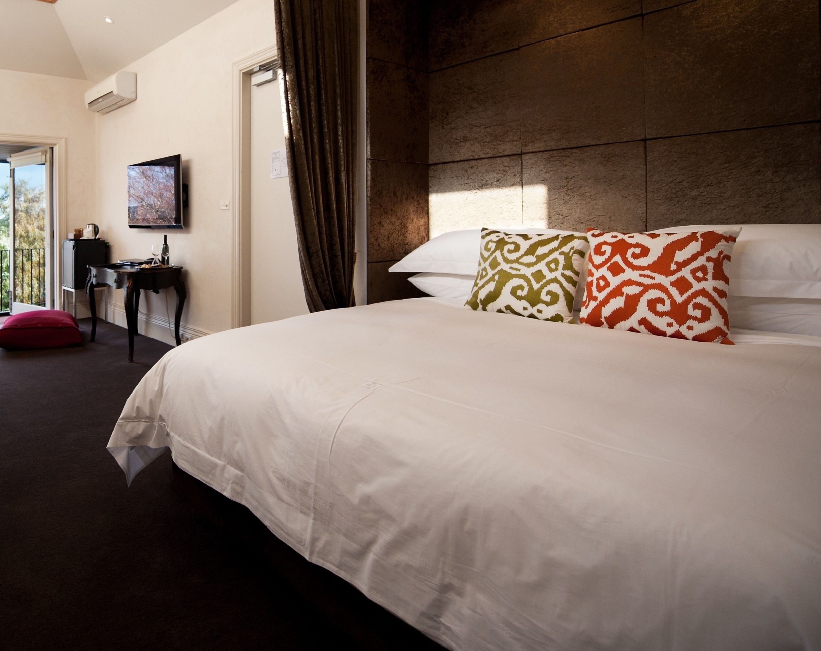 Una habitación de hotel con una cama grande, un escritorio y un televisor en la pared.