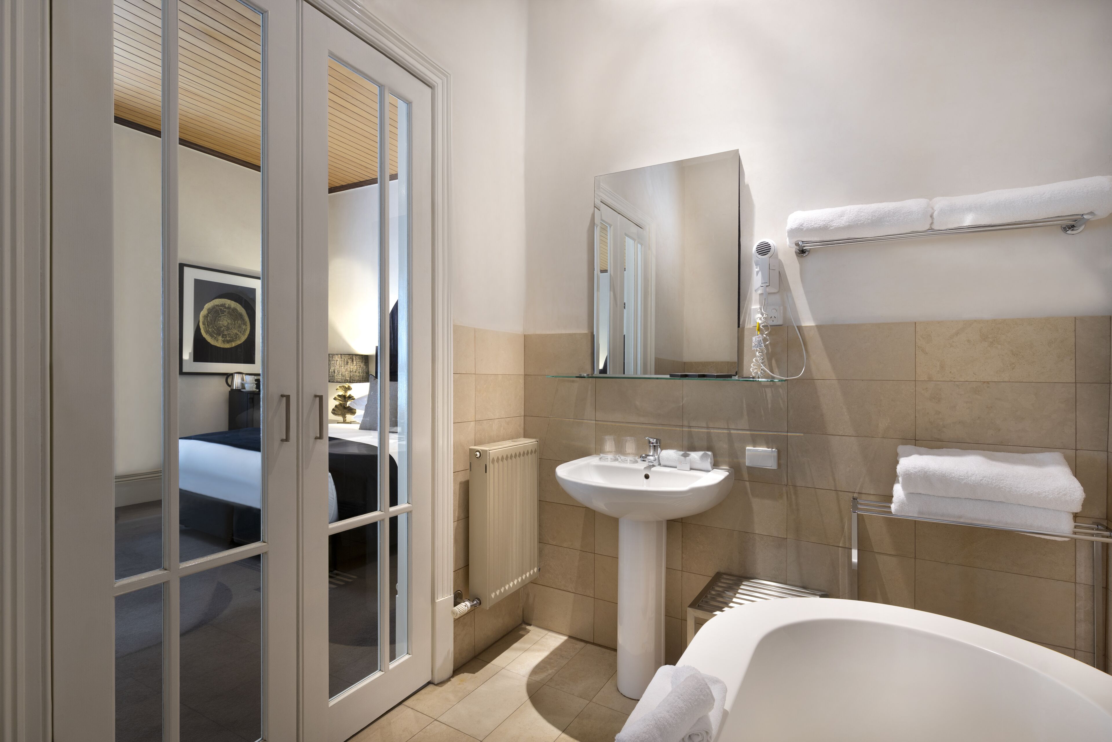 Un baño moderno con bañera, lavamanos y espejo.