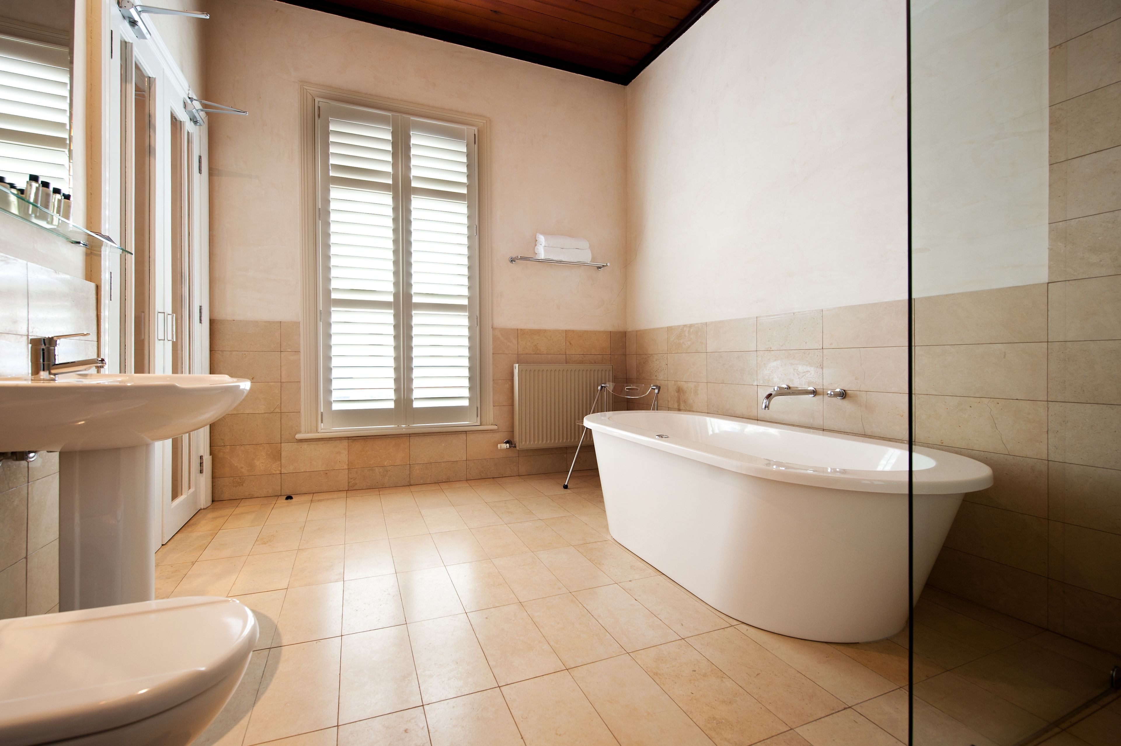 A bathroom with a bathtub, a sink, and a window with blinds.