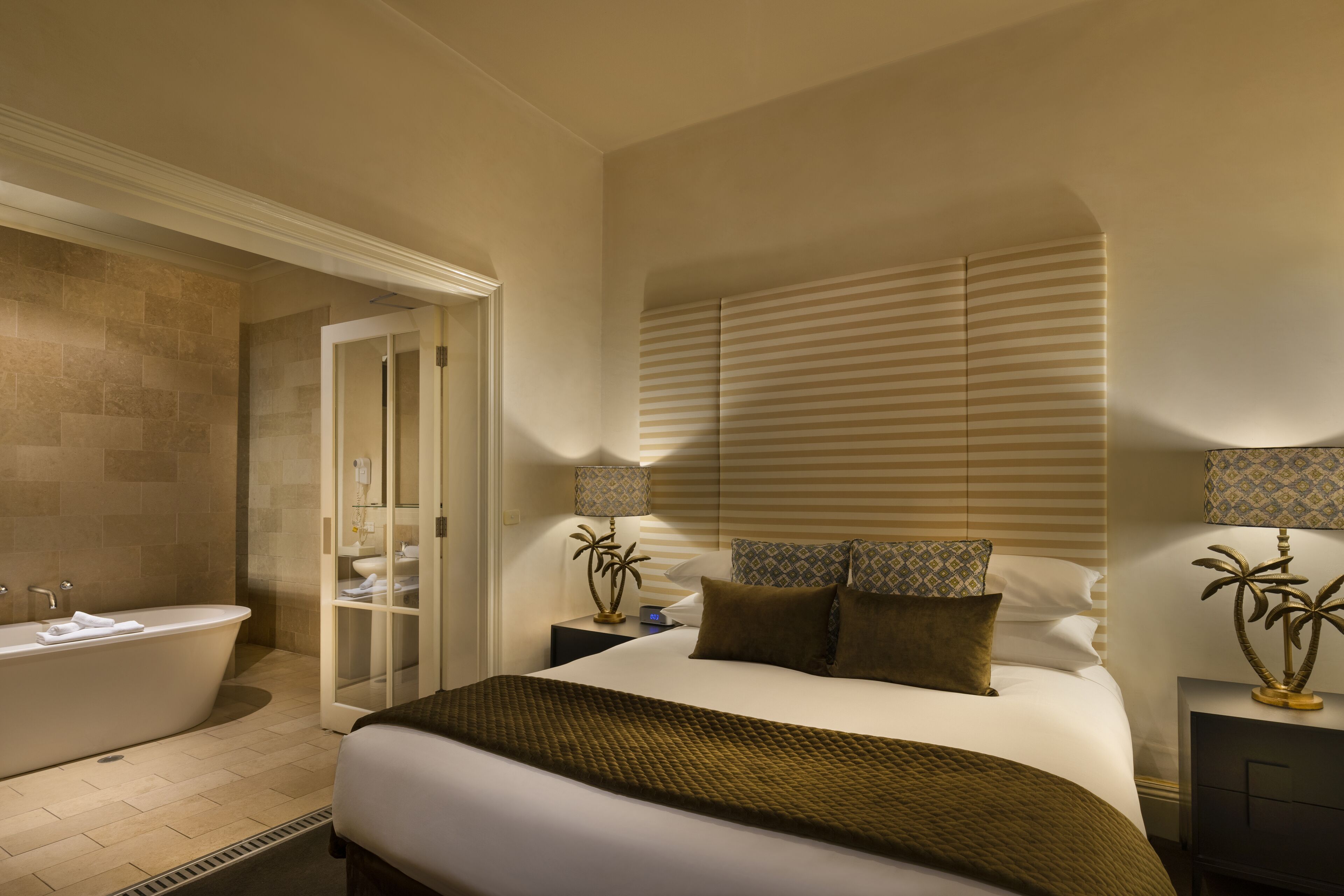 A hotel room with a large bed, a bathtub, and a walk-in closet.