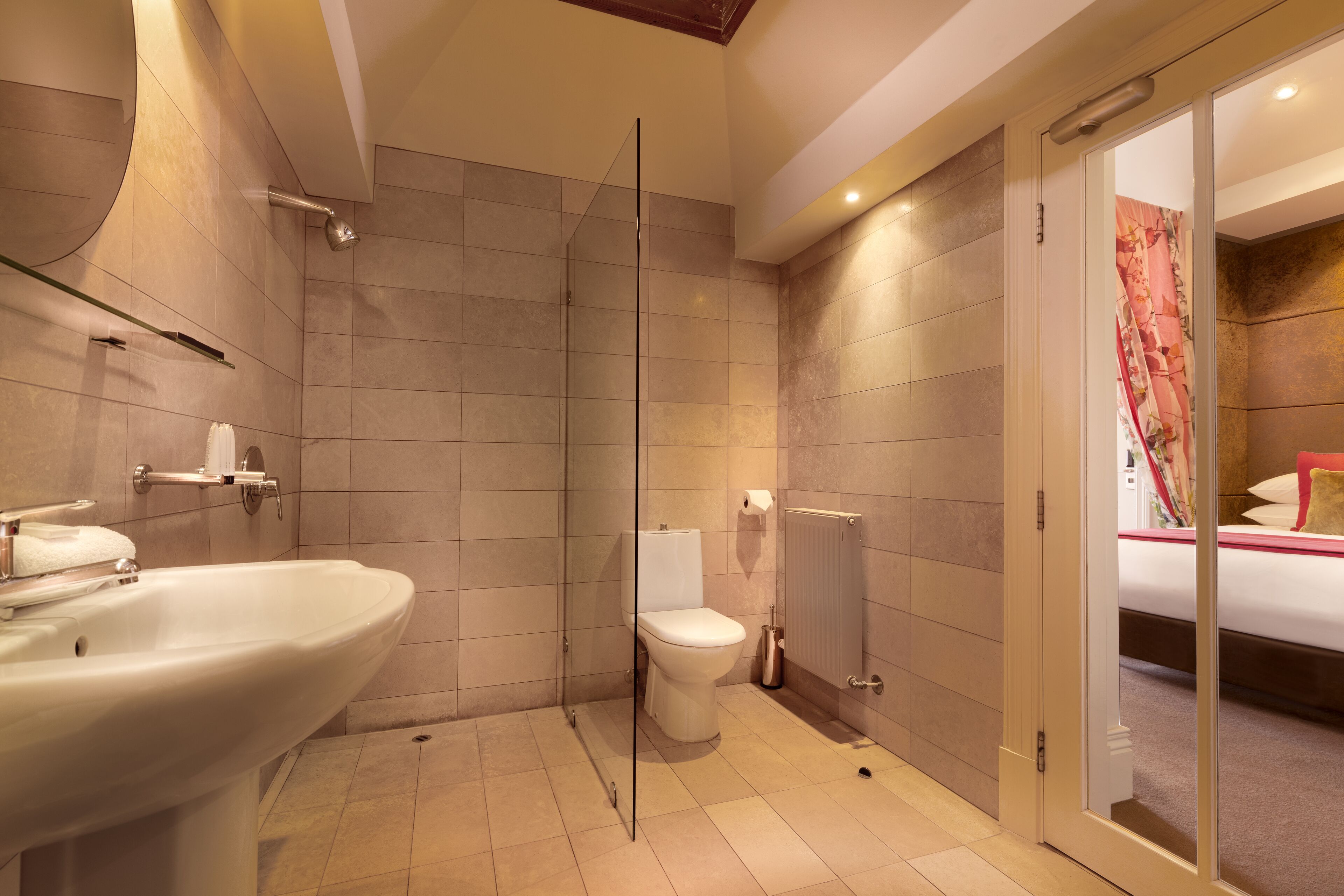 A modern bathroom with a glass shower enclosure, a white sink, and a toilet.