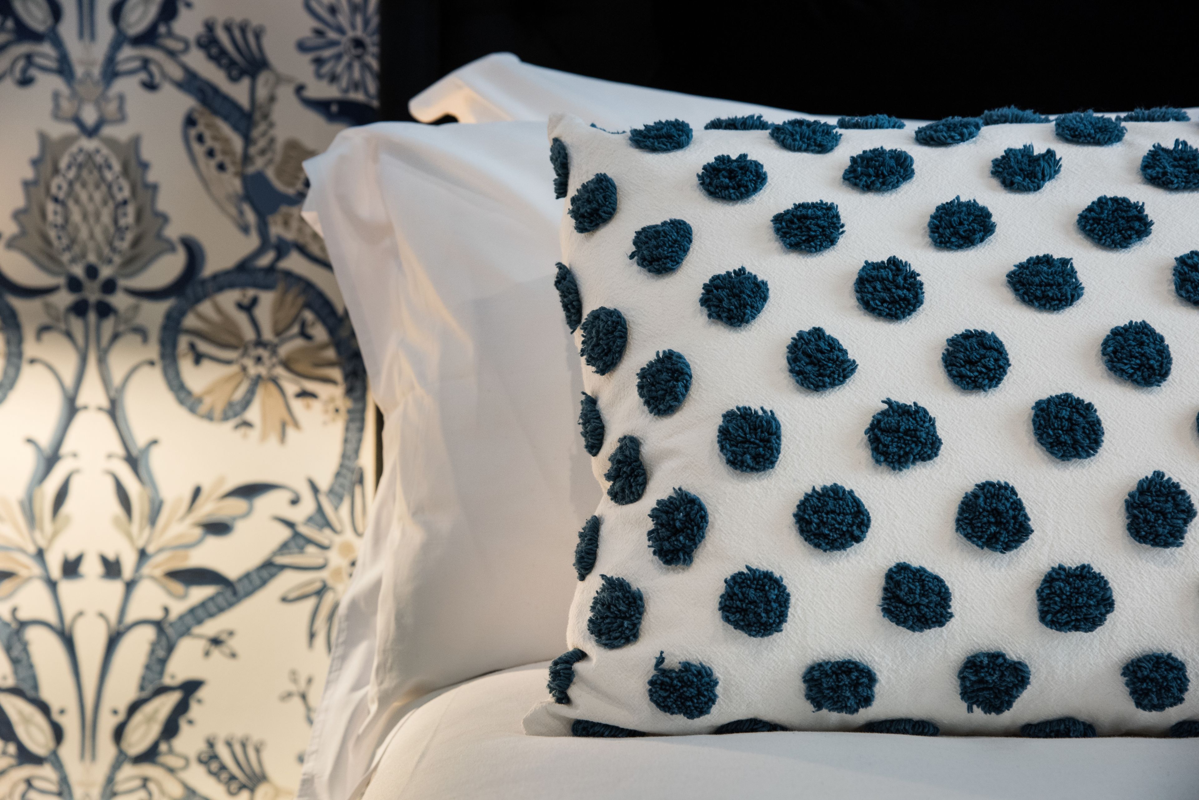 Een wit kussen met blauwe stippen en een wit kussen met een blauw bloemenmotief.