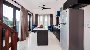 A modern kitchen with a central island, a refrigerator, and a ceiling fan. - Villa Keluarga (Lembongan Island)