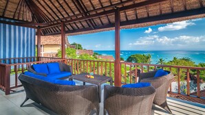 A covered outdoor seating area with wicker furniture and a view of the ocean. - Villa Keluarga (Lembongan Island)