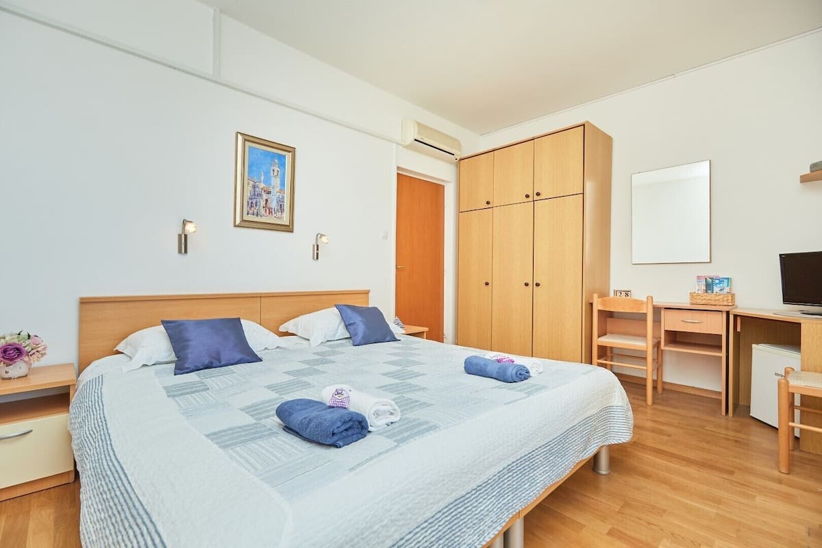 Een hotelkamer met een bed, een bureau, een kledingkast en een televisie.