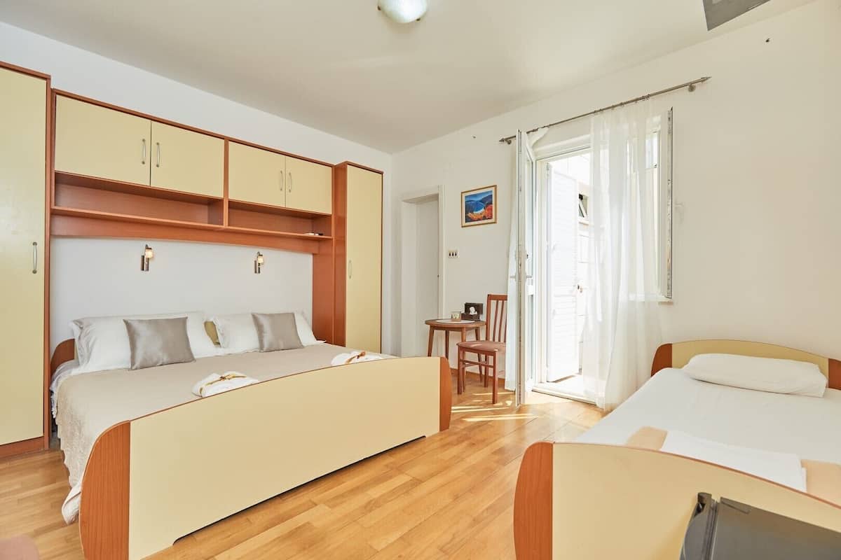 Een slaapkamer met een bed, bureau en stoel. Er is een raam met gordijnen en een schilderij aan de muur.