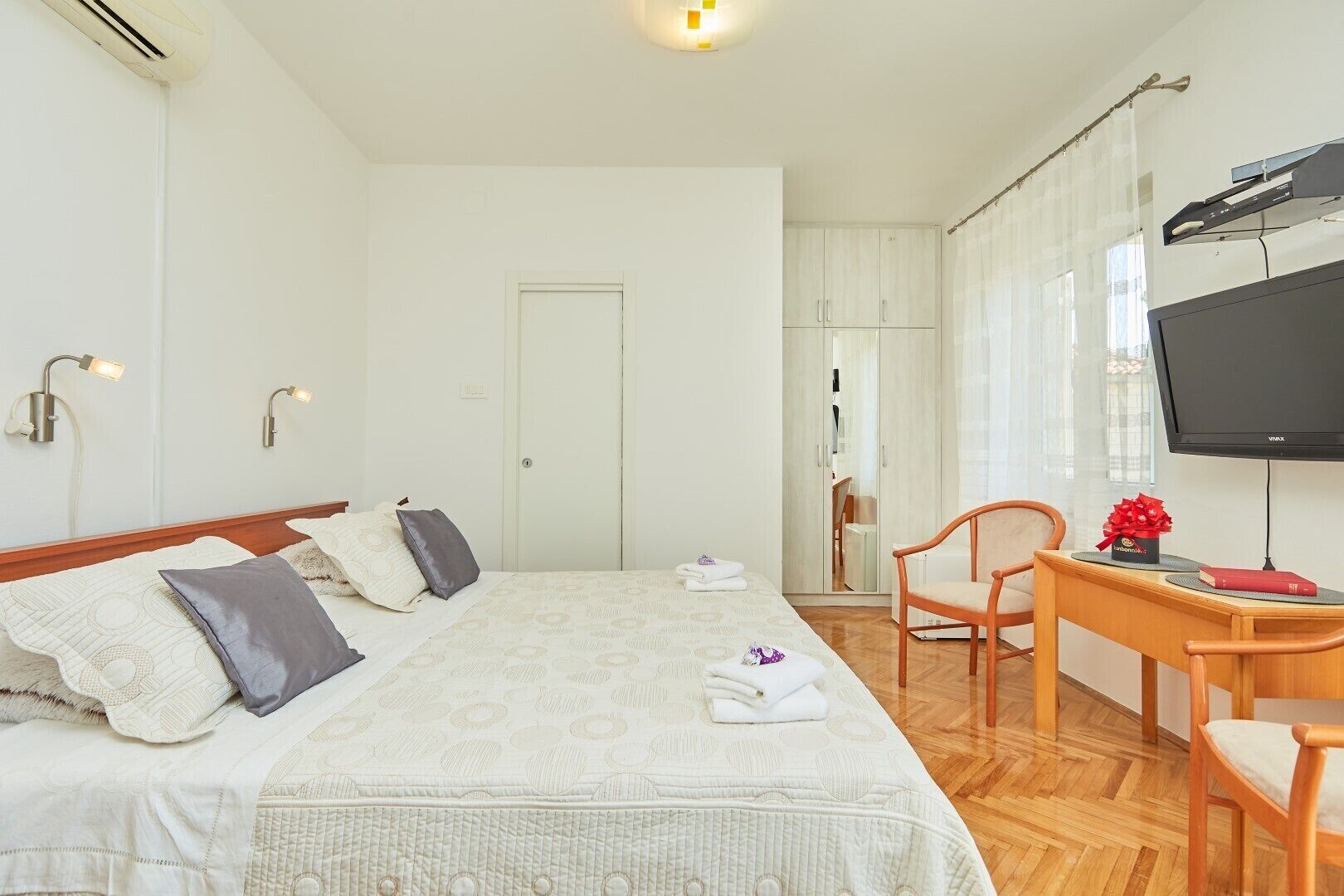 Una camera d'albergo con un letto, una scrivania, una sedia, una televisione e un armadio.