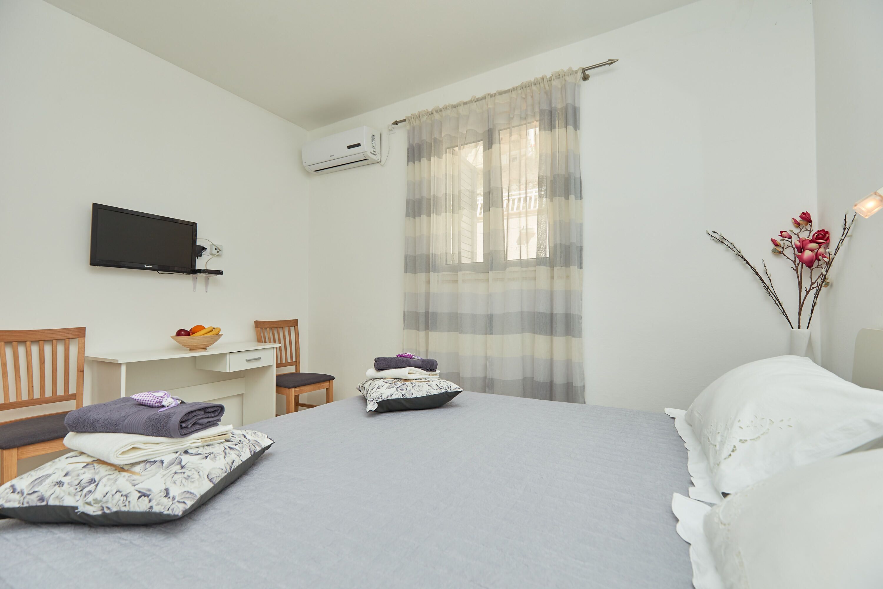 Habitación de hotel con dos camas, un escritorio, una silla, un televisor y una ventana con cortinas.