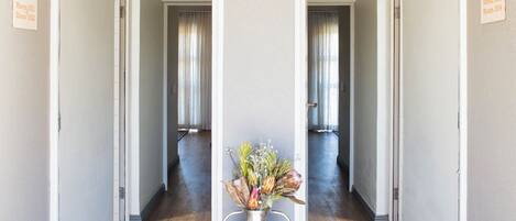 A hallway with two mirrored doors, each labeled with room numbers 3001 and 3003. A metal vase with flowers is placed on the floor in the center.